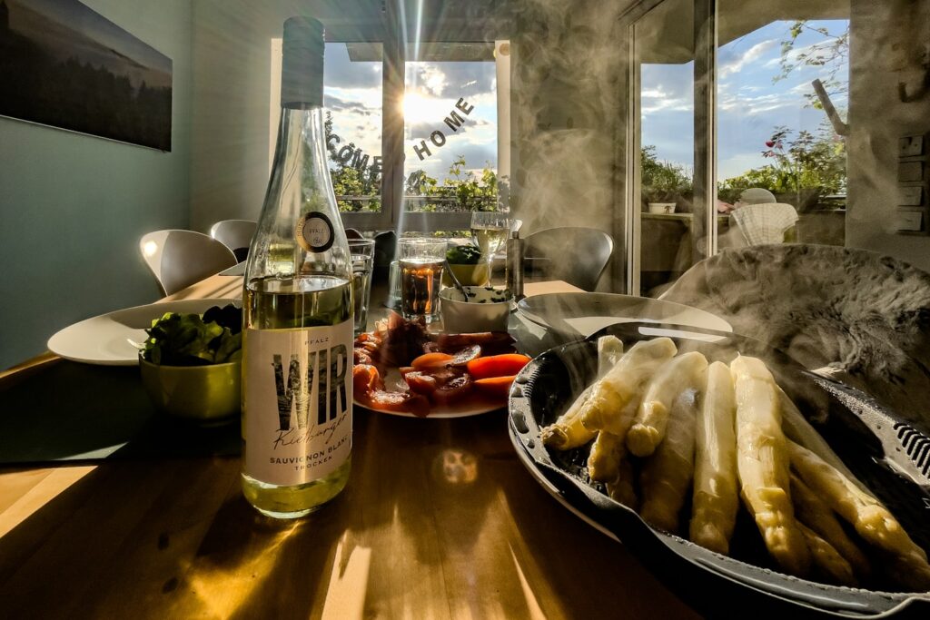 A bottle of white wine and asparagus on a table.